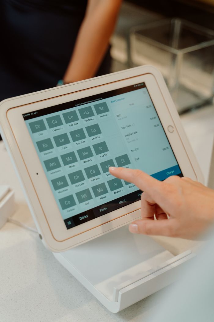 Services Close-up of a touchscreen tablet used as an order terminal with a hand interacting, featuring modern technology.
